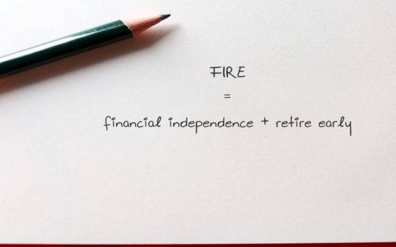 a pen on a piece of paper that says FIRE - financial independence + retire early
