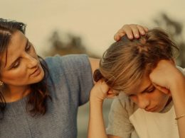 A mother and her son with his head in his hands