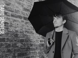 Dario with an umbrella against a brick wall