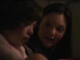 A woman and a girl talk in a drakened room