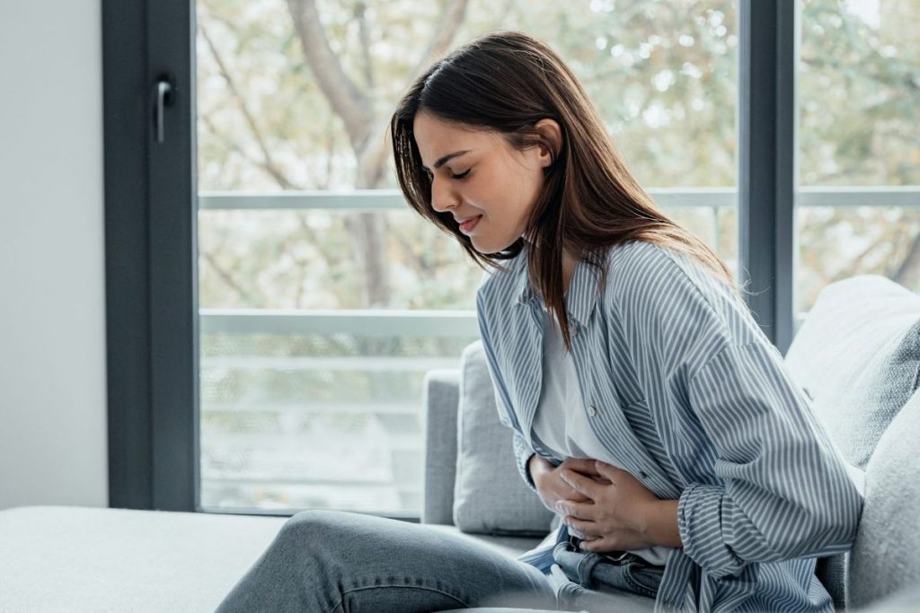 A young woman holds her stomach