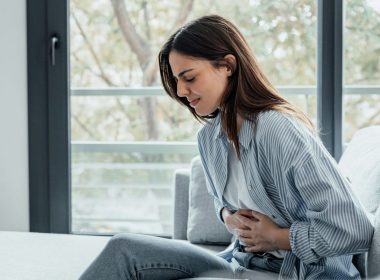 A young woman holds her stomach