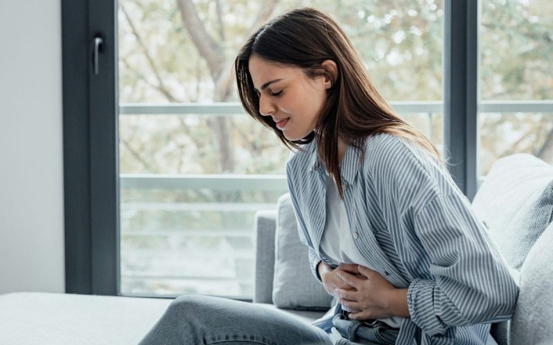 A young woman holds her stomach