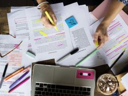 A desk and papers with lots of pens and highlighted information