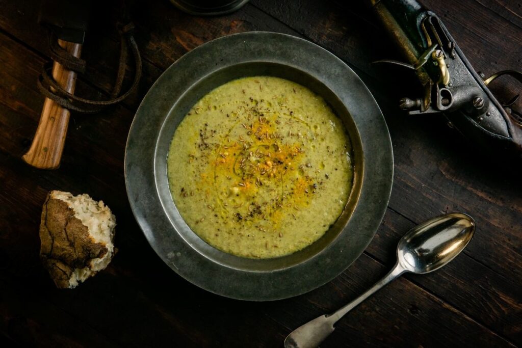A tureen of soup on a table with an old-fashioned pistol