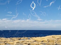 The salt pans and the sea with script in the sky