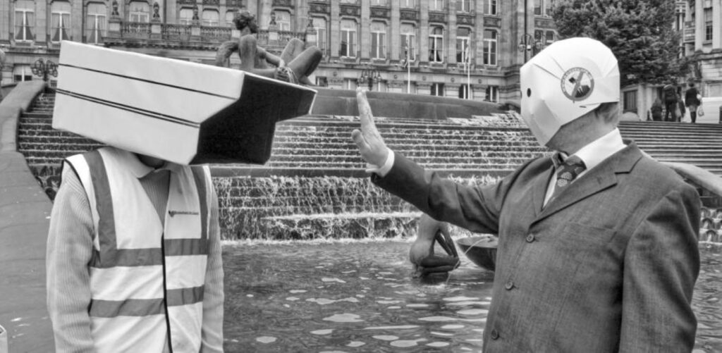 A man puts his hand up to a sman earing a security camera helmet
