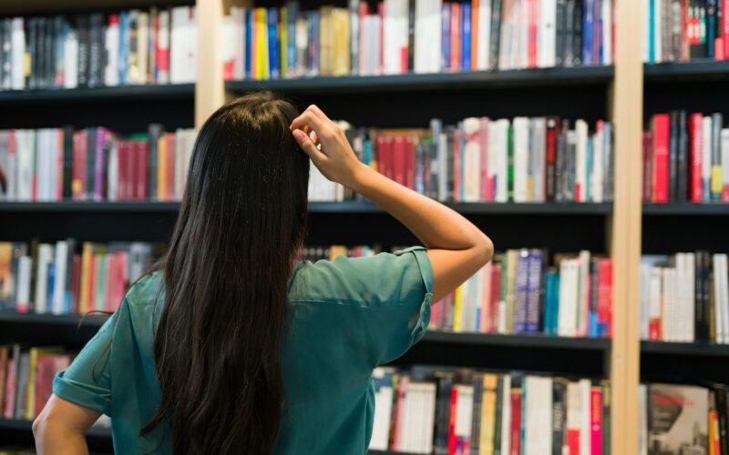 a woman looking at shelves of books