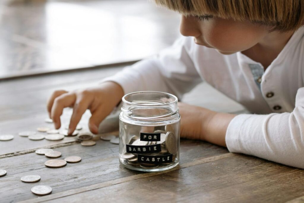 A child and a jam jar of coins
