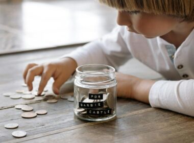 A child and a jam jar of coins