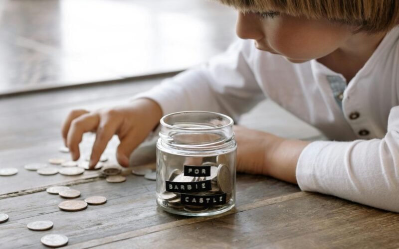 A child and a jam jar of coins