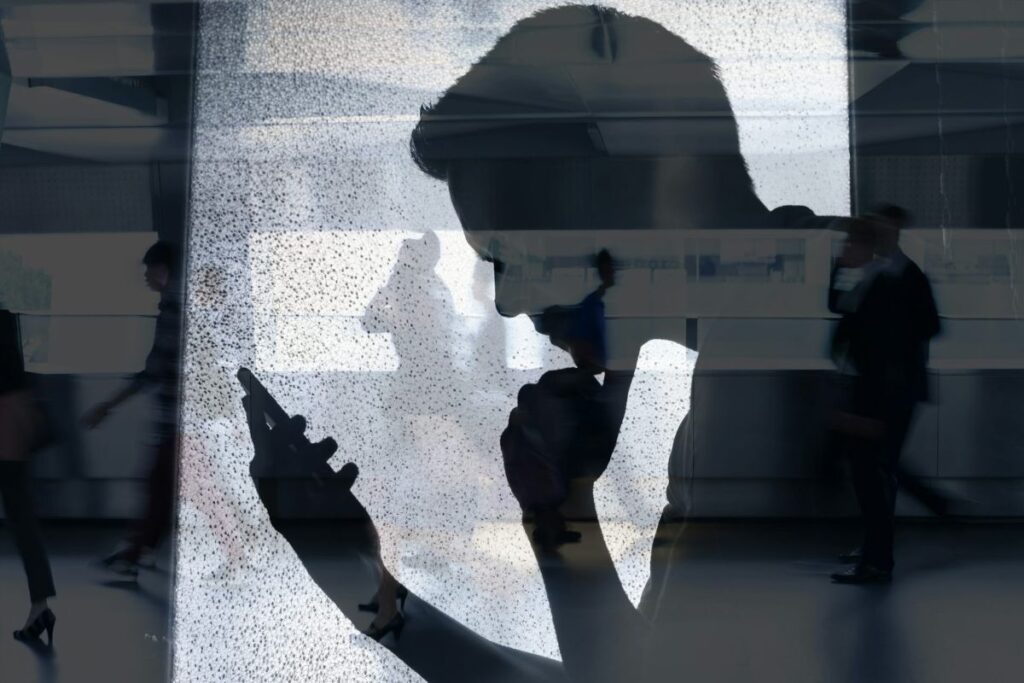 The silhouette of a man reading his phone