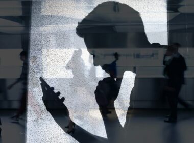 The silhouette of a man reading his phone