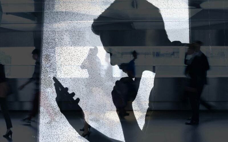 The silhouette of a man reading his phone