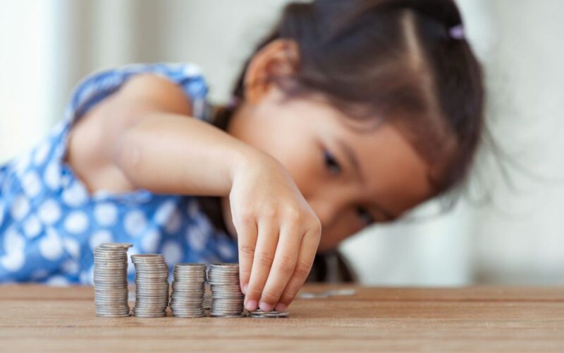 a child lining up piles of coins