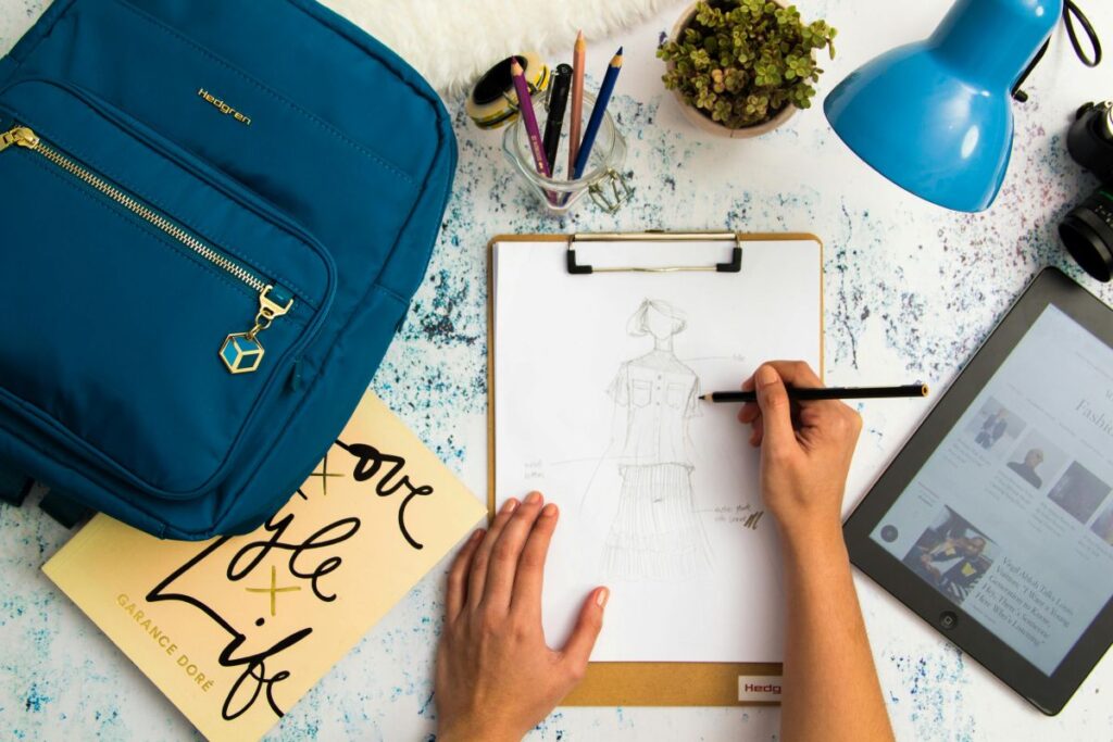 person-sketching-dress-on-printer-paper-with-clip-board
