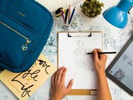 person-sketching-dress-on-printer-paper-with-clip-board