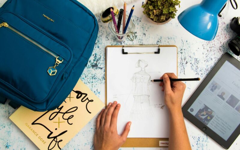 person-sketching-dress-on-printer-paper-with-clip-board