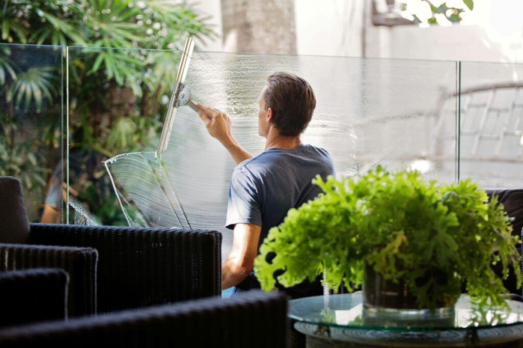 A man cleans the glass on a balcony