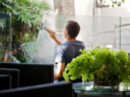 A man cleans the glass on a balcony