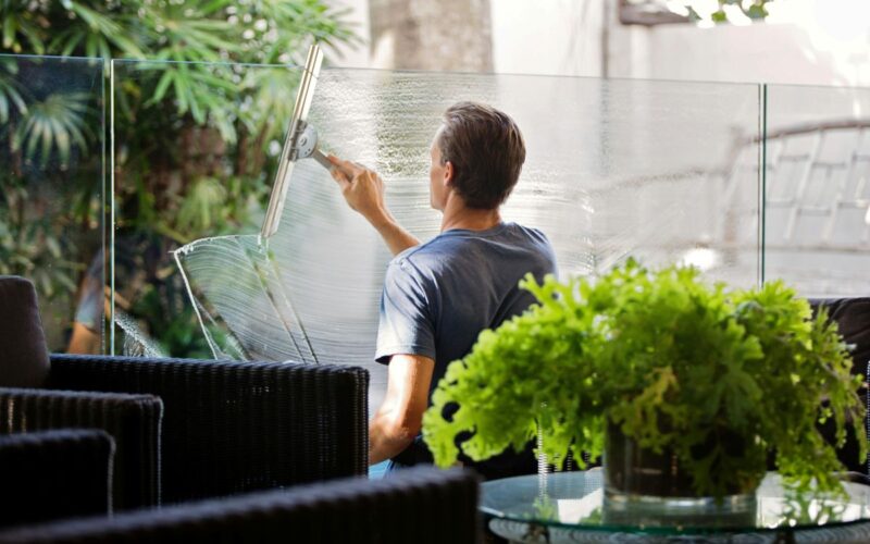 A man cleans the glass on a balcony