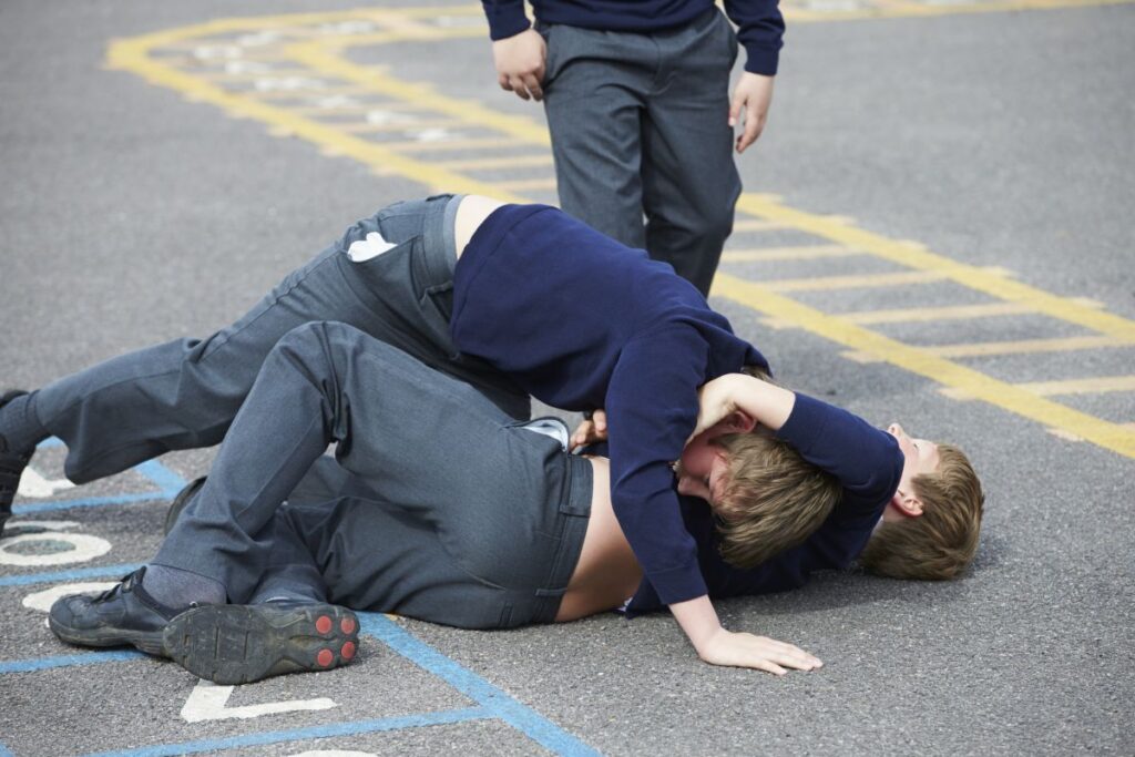 Two boys fighting in a school playground