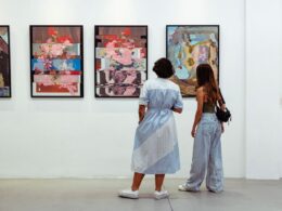 two women look at paintings on a crisp white wall