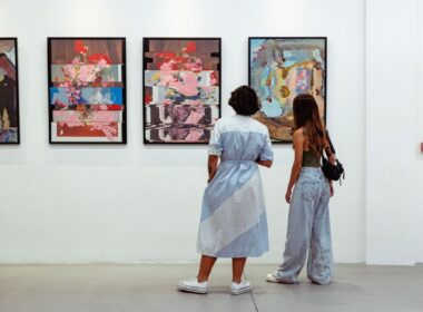 two women look at paintings on a crisp white wall