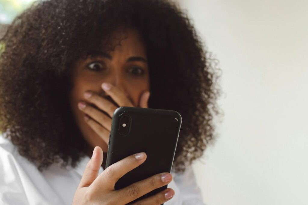 A woman looks shocked as she looks at her phone