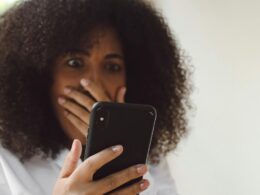 A woman looks shocked as she looks at her phone